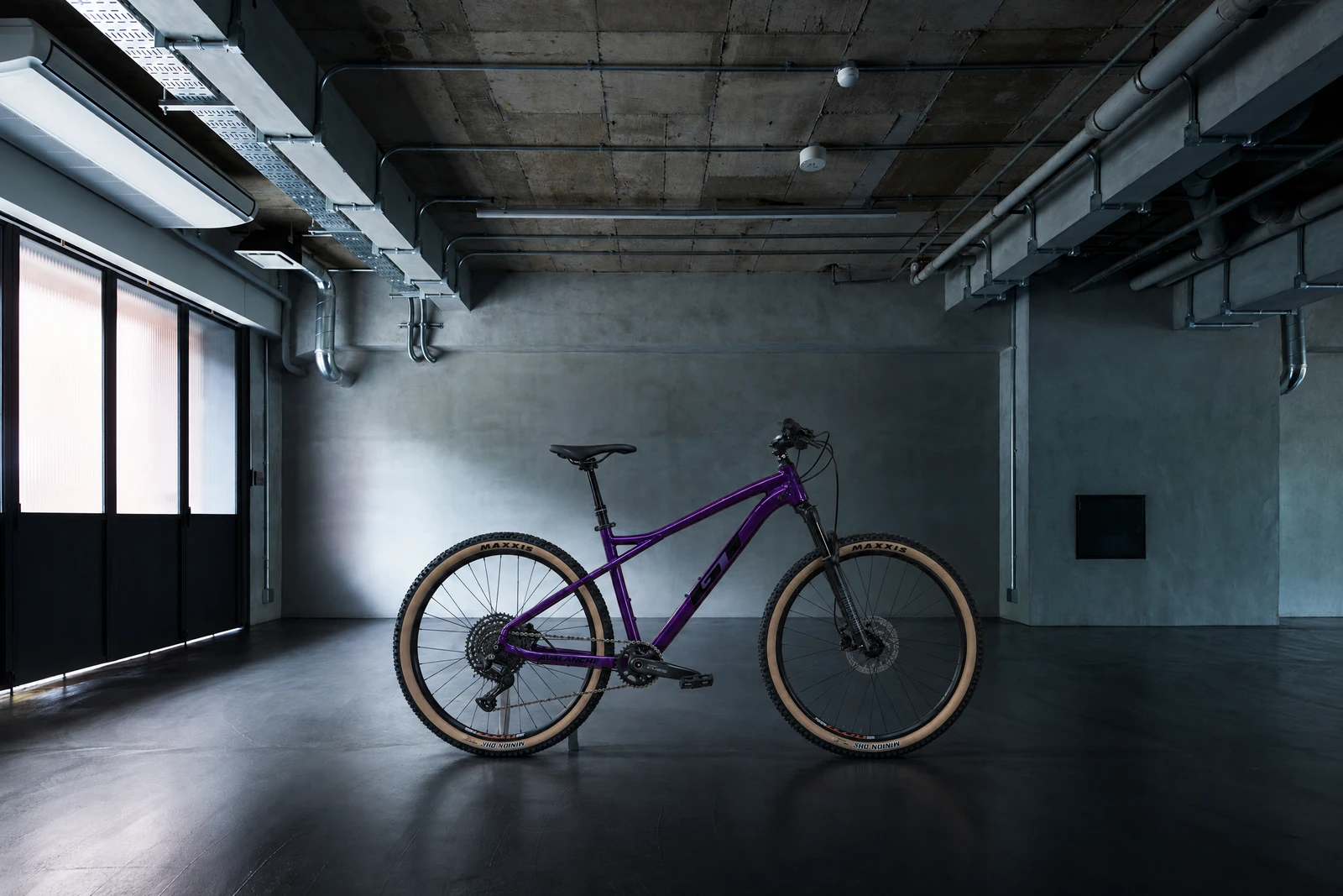 コンクリートの室内に置かれた紫フレームの自転車の完成イメージ